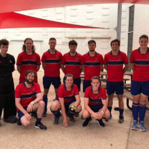 Group of 10 men in a red t-shirt standing and kneeling for a photo 