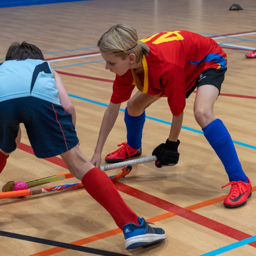 Young boy tackling opposition in indoor hockey